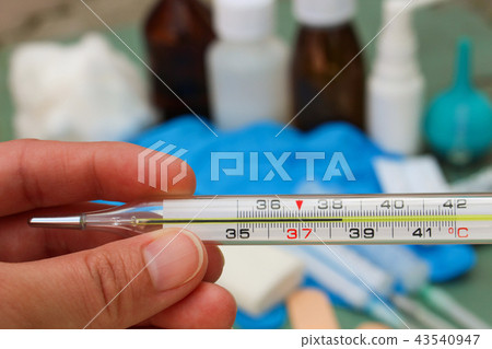 Hand holds thermometer. Body temperature of 38.4 C 43540947