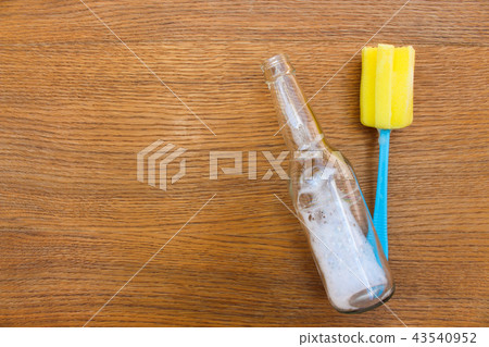 Brush for washing dishes and bottle on table. 43540952