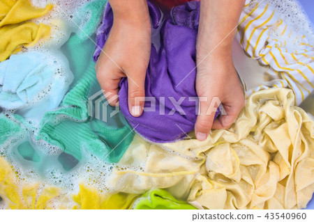 Female hands wash colored clothes in basin. 43540960