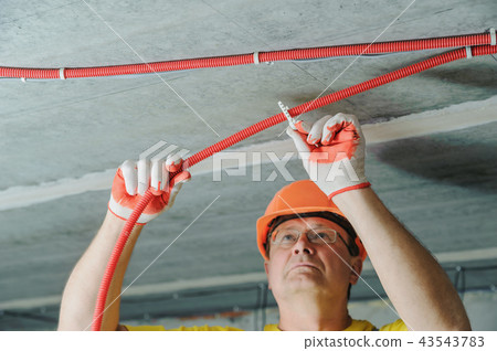 The worker is plastering the electric tubes. 43543783