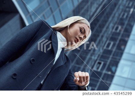 Woman looking at her wrist watch while going to office checking time on the city background Woman looking at her wrist watch while going to office checking time on the city background 43545299