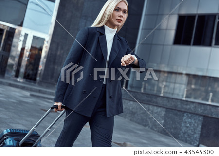 Woman looking at her wrist watch while going to office checking time on the city background Woman looking at her wrist watch while going to office checking time on the city background 43545300
