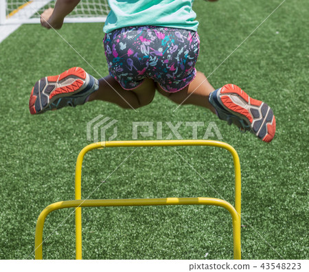 Split legs jumping over yellow mini hurdles Split legs jumping over yellow mini hurdles 43548223