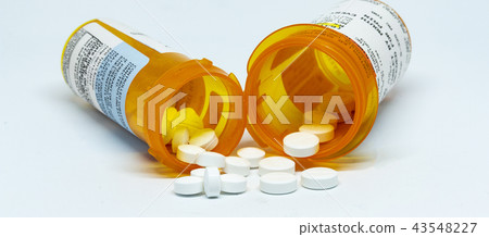 Two pain oill bottles with pills spilling out 43548227