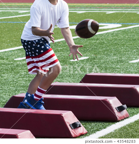 Football boy training in flag shorts catching ball 43548283