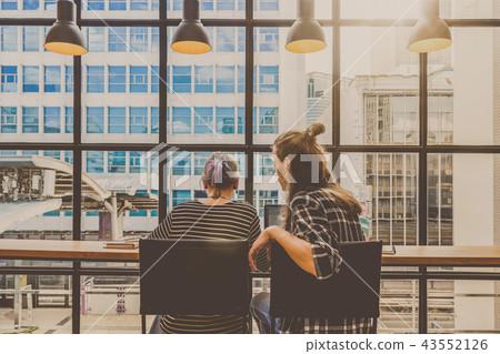 Backside of Hipster young couple freelancer using smart Laptop for working in the Loft cafe workplace. Creative Startup and entrepreneur business concept Backside of Hipster young couple freelancer using smart Laptop for working in the Loft cafe workplace. Creative Startup and entrepreneur business concept 43552126