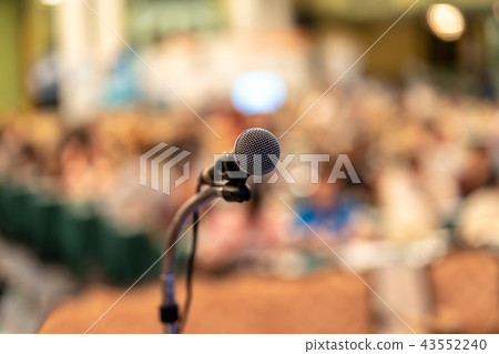 Microphone over the Abstract blurred photo of conference hall or seminar room with audience background, education and learning concept Microphone over the Abstract blurred photo of conference hall or seminar room with audience background, education and learning concept 43552240
