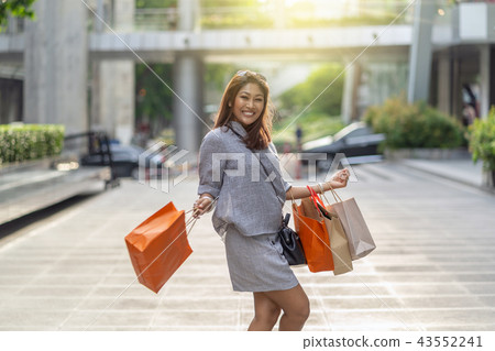 Portrait of Happy Asian woman walking and holding the shopping bag in downtown around shopping center, fashion concept Portrait of Happy Asian woman walking and holding the shopping bag in downtown around shopping center, fashion concept 43552241
