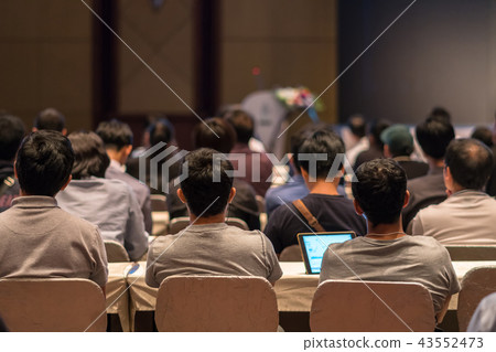 Rear side of Audiences sitting and listening the speackers on the stage in low light conference hall, event and seminar concept Rear side of Audiences sitting and listening the speackers on the stage in low light conference hall, event and seminar concept 43552473
