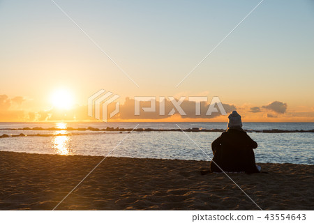 Happy woman sitting on cold beach in Spain. 43554643