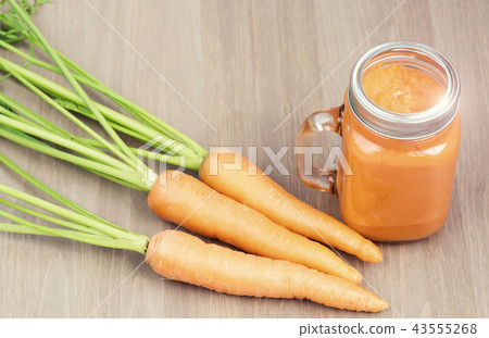 A glass of healthy carrot smoothie with carrots on wooden background 43555268