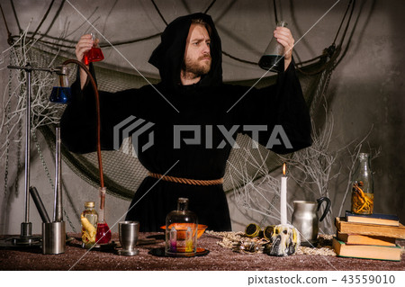 medieval scientist looks at flasks in laboratory. medieval scientist looks at flasks in laboratory. 43559010