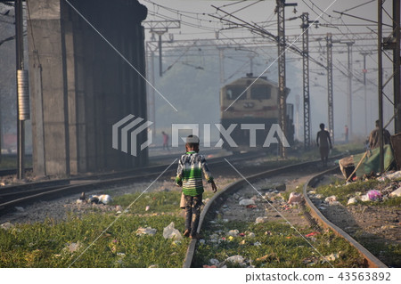 A boy playing walking on a slum track along the Indian capital Delhi railway track An Indian railway approaching from a distance 43563892