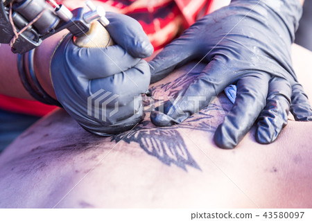 Closeup of tattoo grafting onto body using tools 43580097