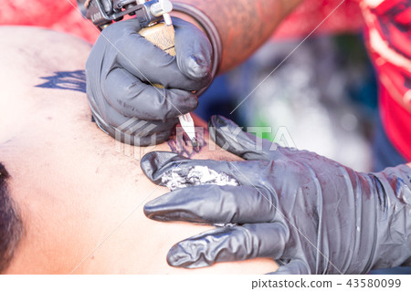 Closeup of tattoo grafting onto body using tools 43580099