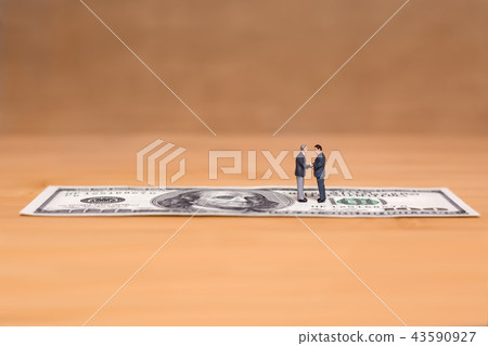 Miniature people and money. Creative concept of a deal. Businessmens shake hands Miniature people and money. Creative concept of a deal. Businessmens shake hands 43590927