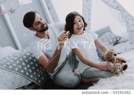 Father Combing Daughter Sitting on Bed in Bedroom Father Combing Daughter Sitting on Bed in Bedroom 43591092