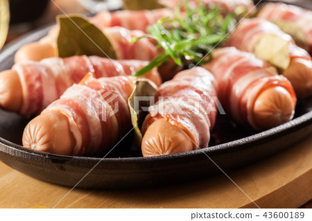 Raw mini sausages wrapped in smoked bacon Raw mini sausages wrapped in smoked bacon 43600189