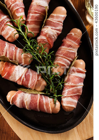 Raw mini sausages wrapped in smoked bacon Raw mini sausages wrapped in smoked bacon 43600190