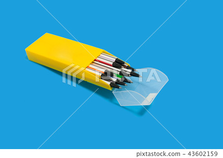 pens in a yellow box on a blue surface pens in a yellow box on a blue surface 43602159