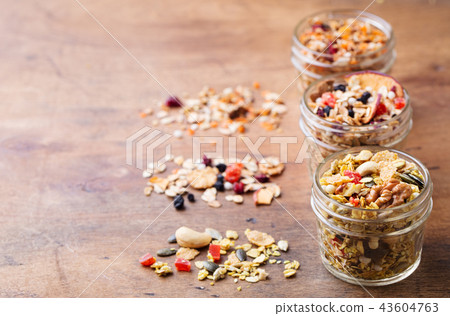 Assortment of granola, muesli in glass jars. Organic oats with apples, berries, nuts. Copy space. 43604763