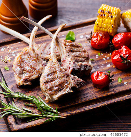 Lamb ribs grilled on cutting board with roasted vegetables. Close up. Lamb ribs grilled on cutting board with roasted vegetables. Close up. 43605472