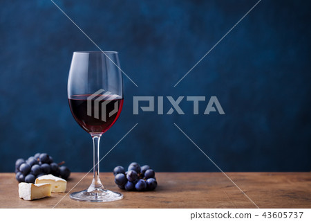 Glass of red wine with fresh grape and cheese on wooden table. Blue background. Copy space. Glass of red wine with fresh grape and cheese on wooden table. Blue background. Copy space. 43605737