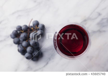 Red wine in glass with fresh grape on marble table background. Top view. 43605740