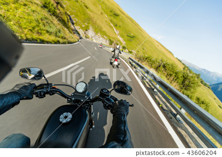 Motorcycle driver riding in Alpine highway, handlebars view, Austria, Europe. 43606204