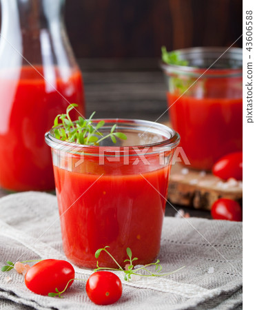 Tomato juice in glass with cress salad, fresh tomatoes on wooden cutting board and grey towel. 43606588