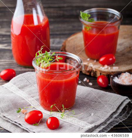 Tomato juice in glass with cress salad, fresh tomatoes on wooden cutting board and grey towel. 43606589