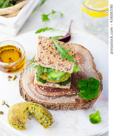 Healthy vegan burger with broccoli and spinach patty on a cutting wooden board. Healthy vegan burger with broccoli and spinach patty on a cutting wooden board. 43606590
