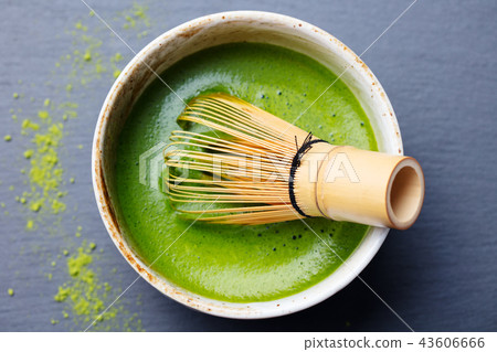 Matcha green tea cooking process in a bowl with bamboo whisk. Black slate background. Top view. 43606666