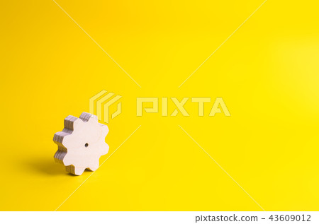 A wooden gear on a yellow background.  43609012