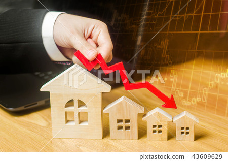 The hand holds a red arrow above the wooden house The hand holds a red arrow above the wooden house 43609629