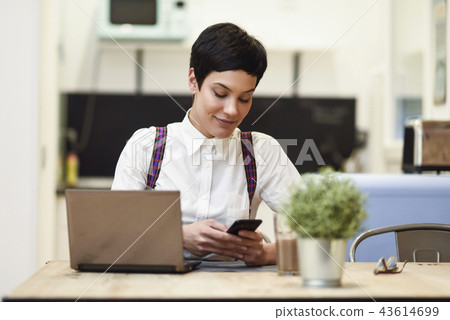 Young businesswoman with very short haircut looking at her smart Young businesswoman with very short haircut looking at her smart 43614699
