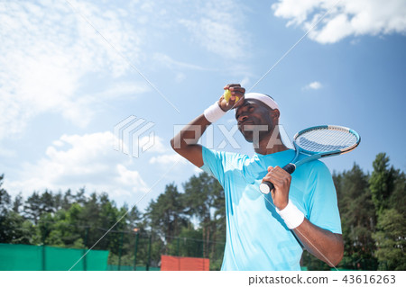 Tennis player is preparing to serve under sun Tennis player is preparing to serve under sun 43616263