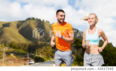 smiling couple running over big sur hills 43617548
