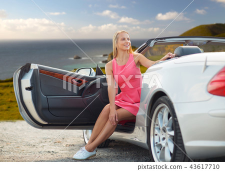 woman posing in convertible car over big sur coast 43617710