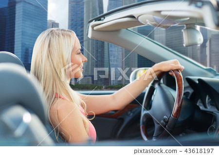 woman driving convertible car over singapore city woman driving convertible car over singapore city 43618197