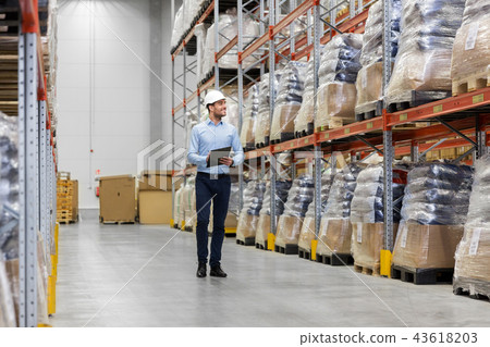 businessman in helmet with clipboard at warehouse 43618203
