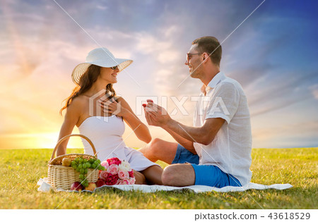 smiling couple with small red gift box at picnic smiling couple with small red gift box at picnic 43618529