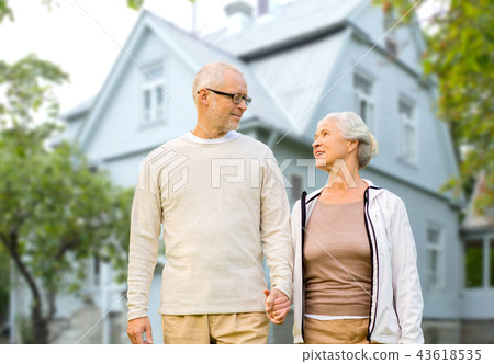 happy senior couple holding hands over house happy senior couple holding hands over house 43618535