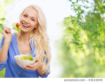 smiling young woman eating vegetable salad 43618949