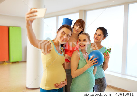 pregnant women taking selfie by smartphone in gym pregnant women taking selfie by smartphone in gym 43619011