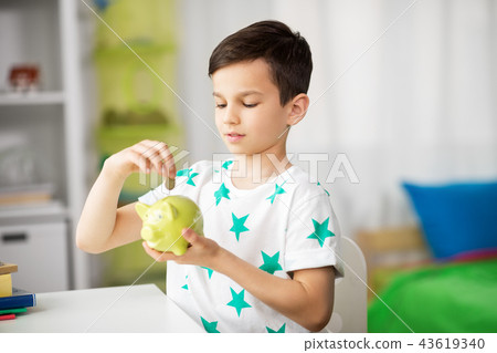little boy putting coin into piggy bank at home 43619340