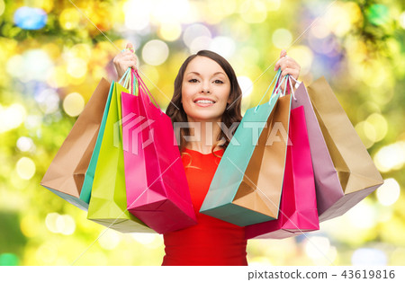 young smiling woman with shopping bags over lights young smiling woman with shopping bags over lights 43619816