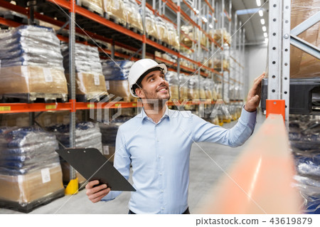 businessman in helmet with clipboard at warehouse businessman in helmet with clipboard at warehouse 43619879