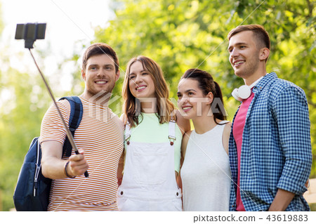 friends take picture by smartphone on selfie stick friends take picture by smartphone on selfie stick 43619883