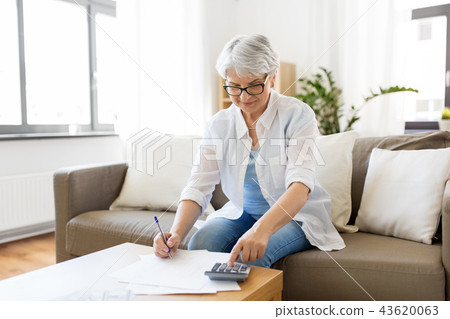 senior woman with money and bills at home senior woman with money and bills at home 43620063